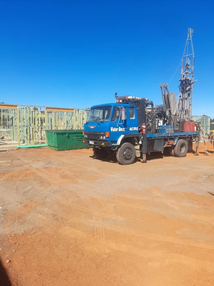 A Blue Truck With a Crane on the Back is Parked in a Dirt Lot — Cheyenne Drilling in Hervey Bay, QLD