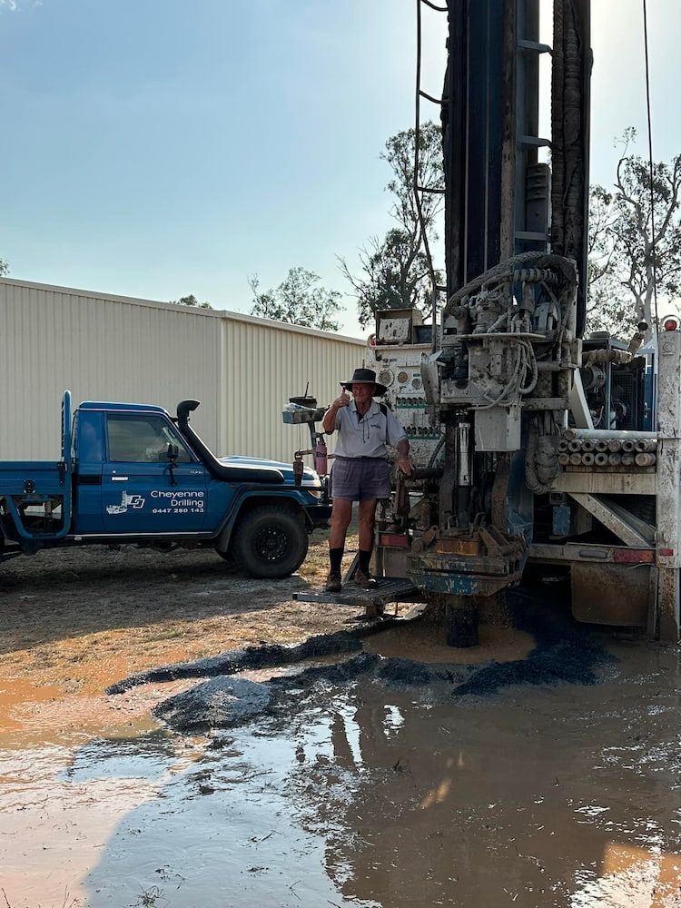 A Man is Standing Next to a Large Machine in a Muddy Area — Cheyenne Drilling in Kingaroy, QLD