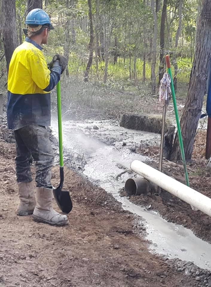 A Man is Standing Next to a Stream Holding a Shovel — Cheyenne Drilling on the Sunshine Coast, QLD