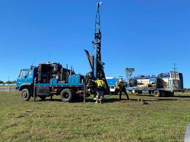 A Blue Truck is Parked in a Grassy Field Next to a Drilling Rig — Cheyenne Drilling on the Sunshine Coast, QLD