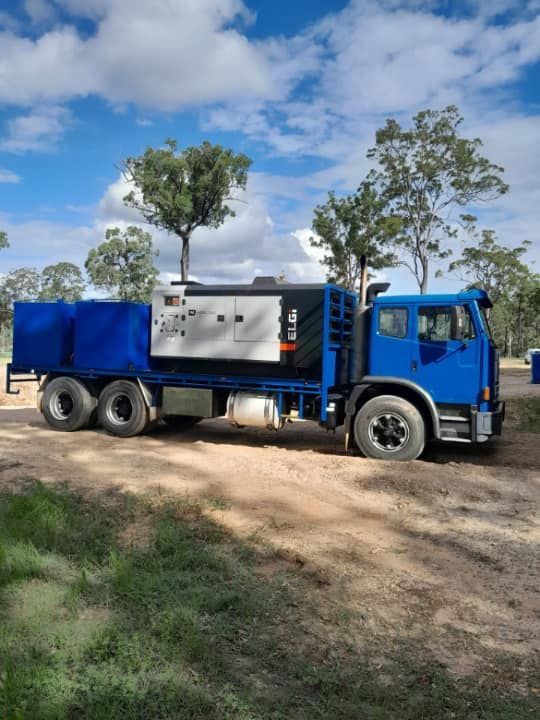 A Blue Truck is Parked in a Dirt Field With Trees in the Background — Cheyenne Drilling on the Sunshine Coast, QLD
