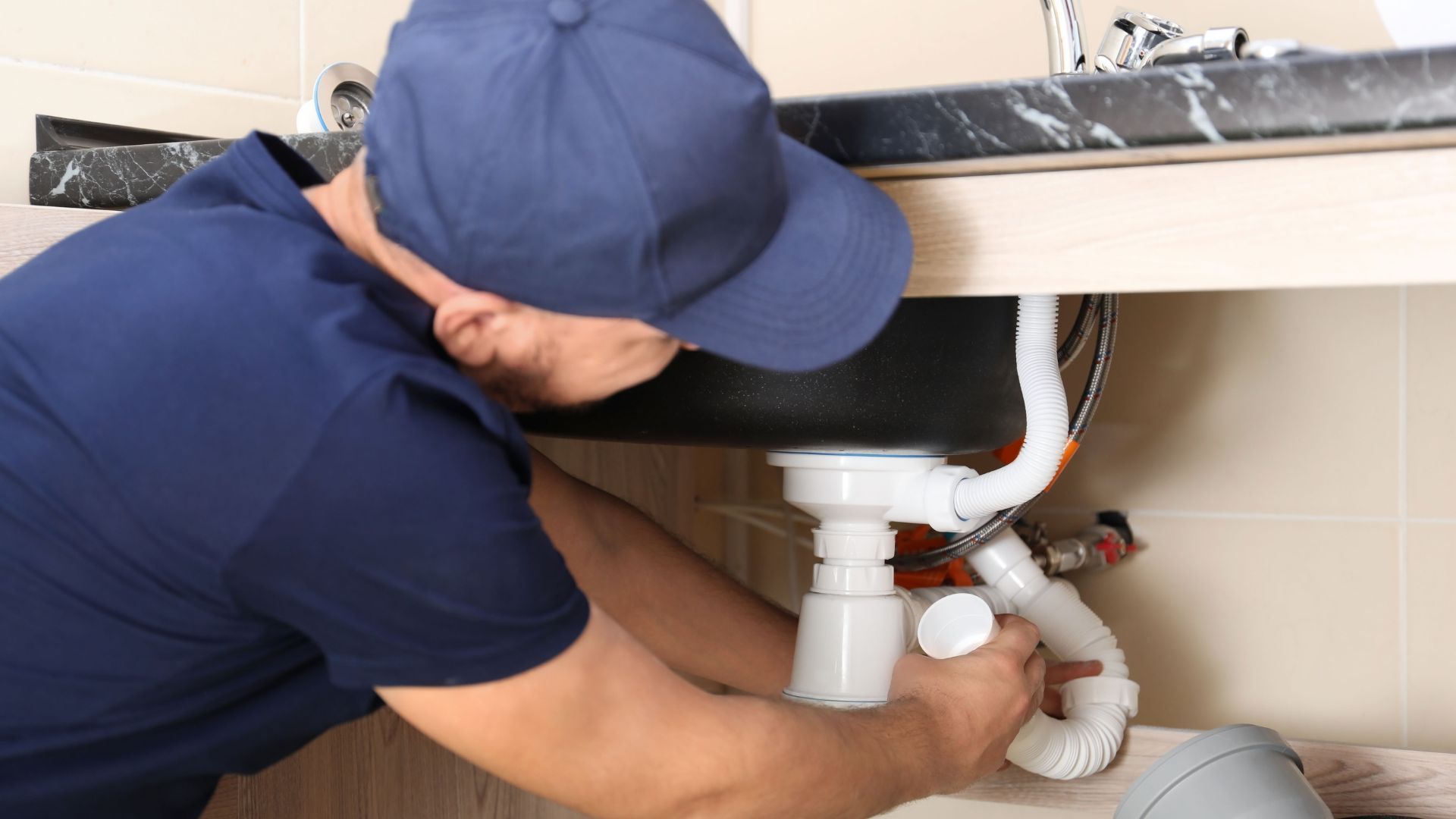 A plumber is fixing a sink in a bathroom.