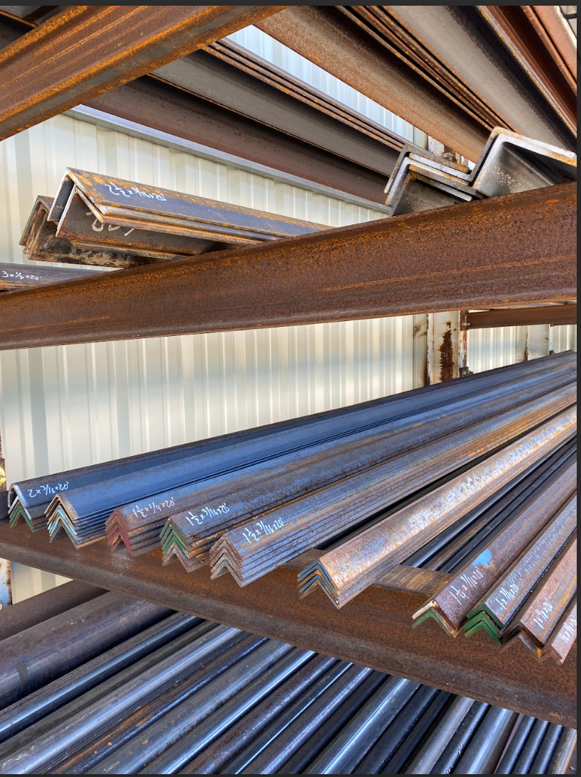 Steel angle bars stacked on rusty shelves.