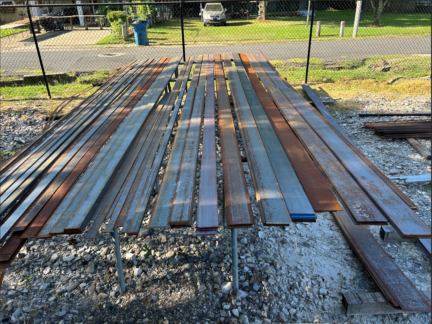 Wooden planks of varying colors and sizes laid out on supports outdoors.