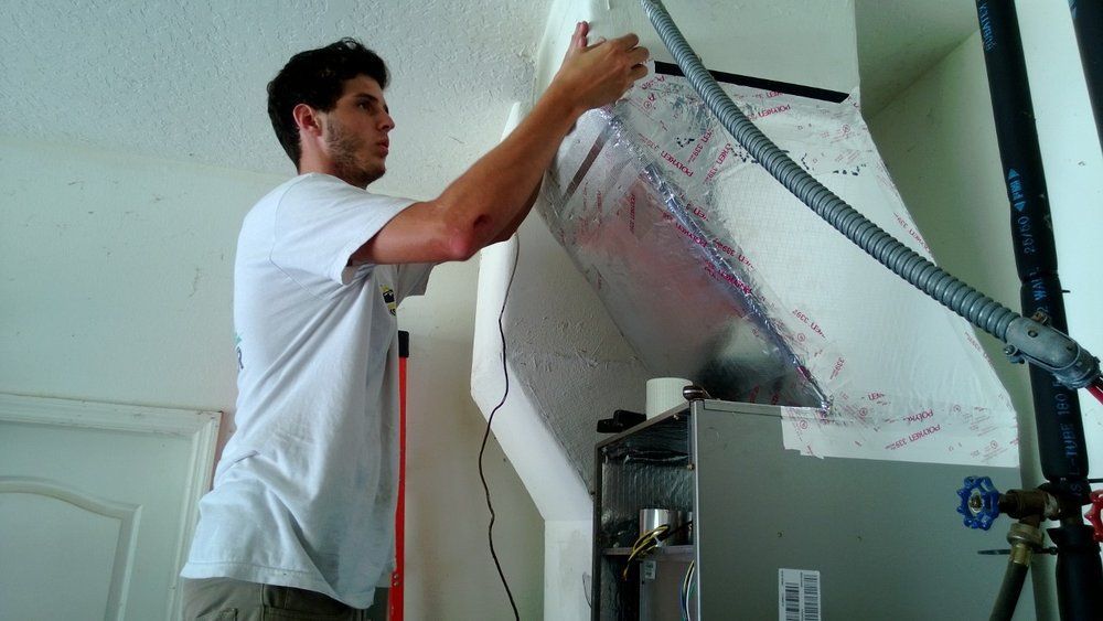 A man is working on an air conditioner in a garage.