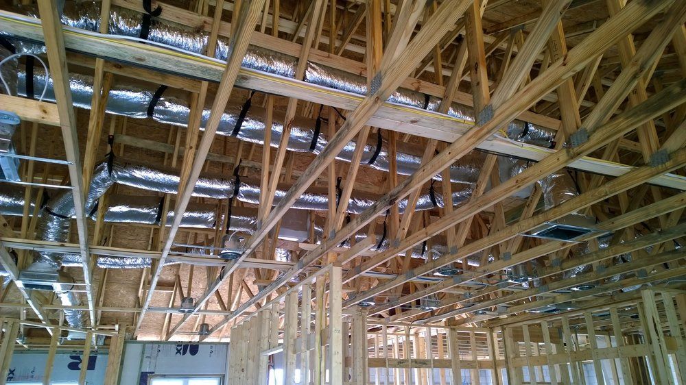 The ceiling of a building under construction with a lot of pipes hanging from it.