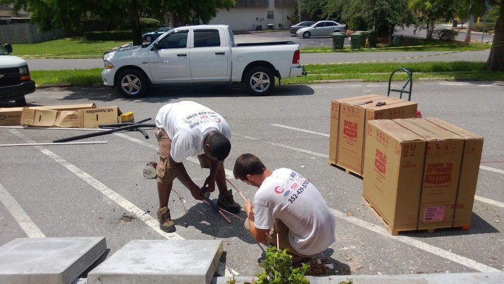 Two men are working in a parking lot in front of a white truck