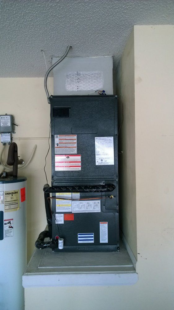A stack of air conditioners sitting on top of each other on a wall next to a water heater.