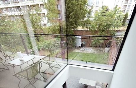 A balcony with tables and chairs and a view of a garden.