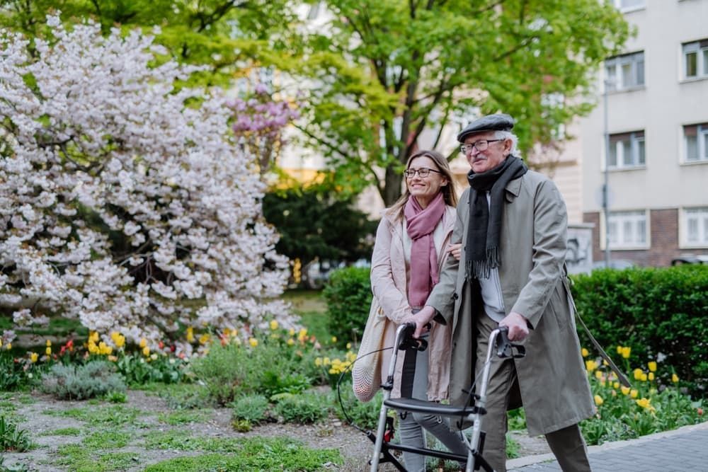 Senior man with walking frame and adult daughter outdoors on a walk in park — Healthcare Equipment in Kurri Kurri