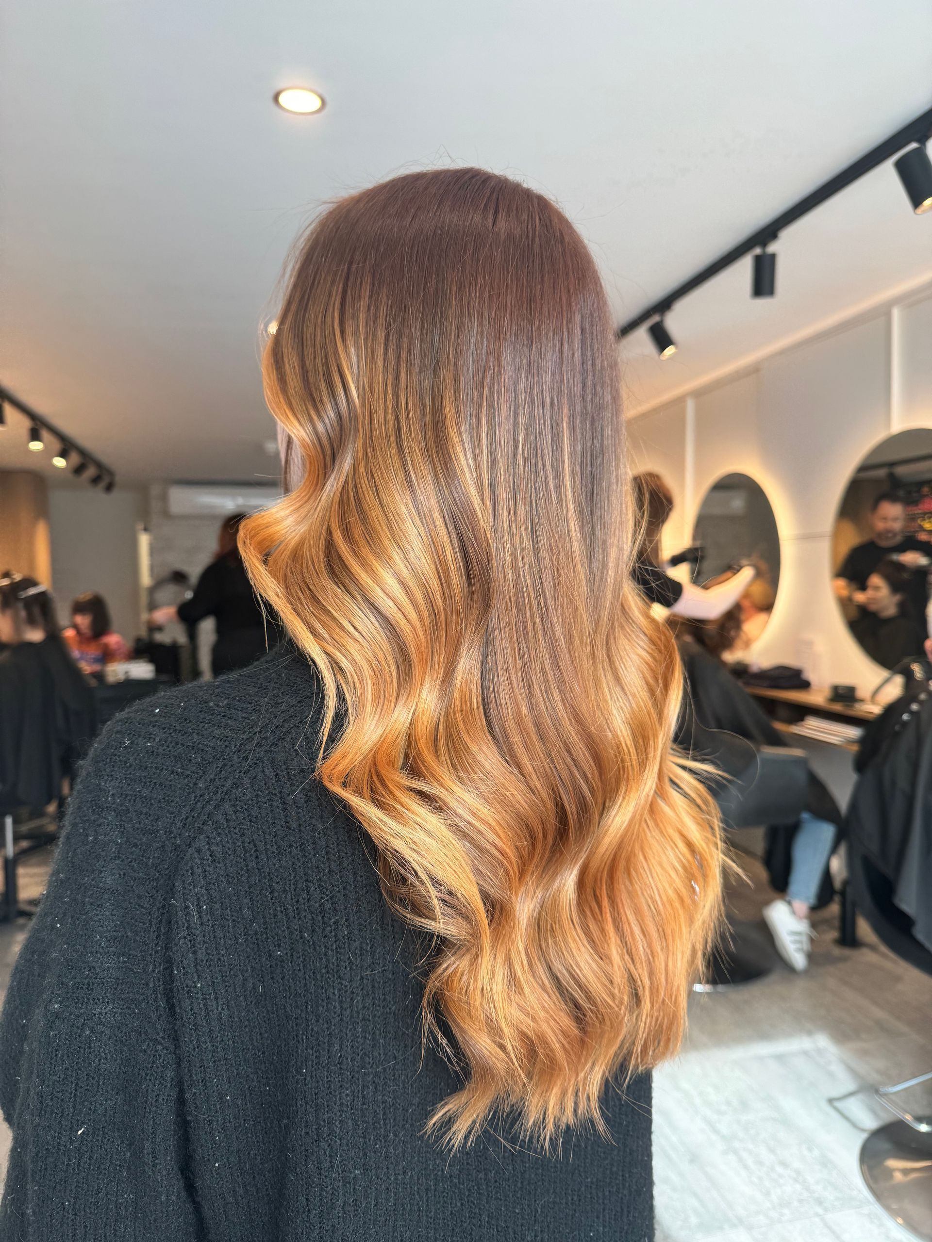 A woman with long brown hair is getting her hair cut in a salon.