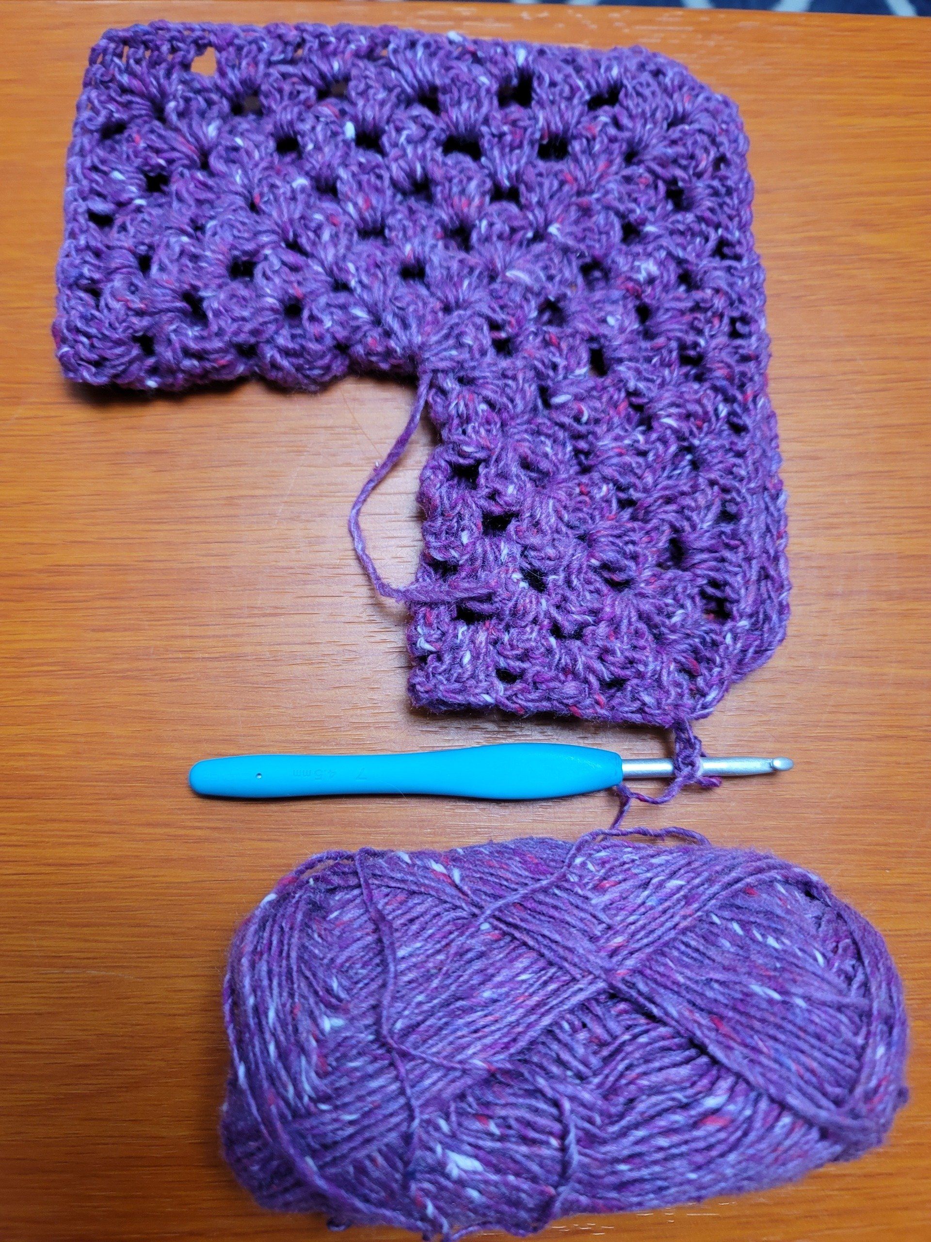 There is a crochet hook and a ball of yarn on the table.