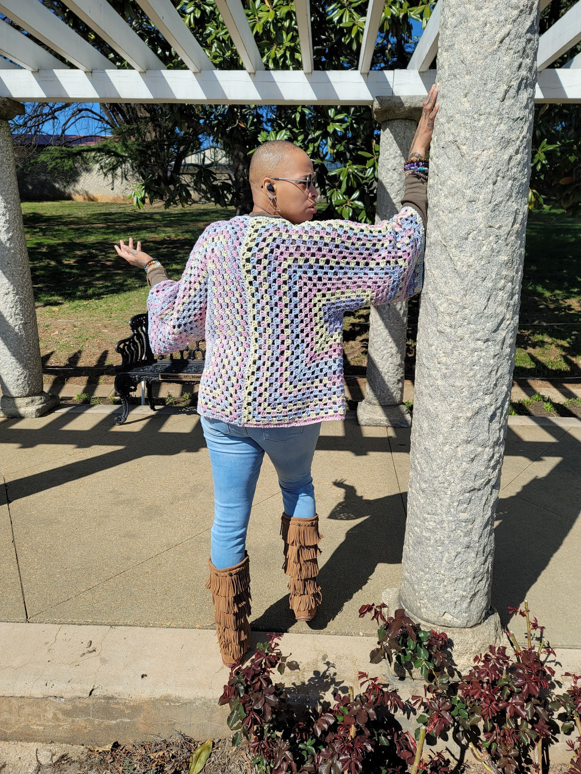 A woman is standing under a pergola in a park.