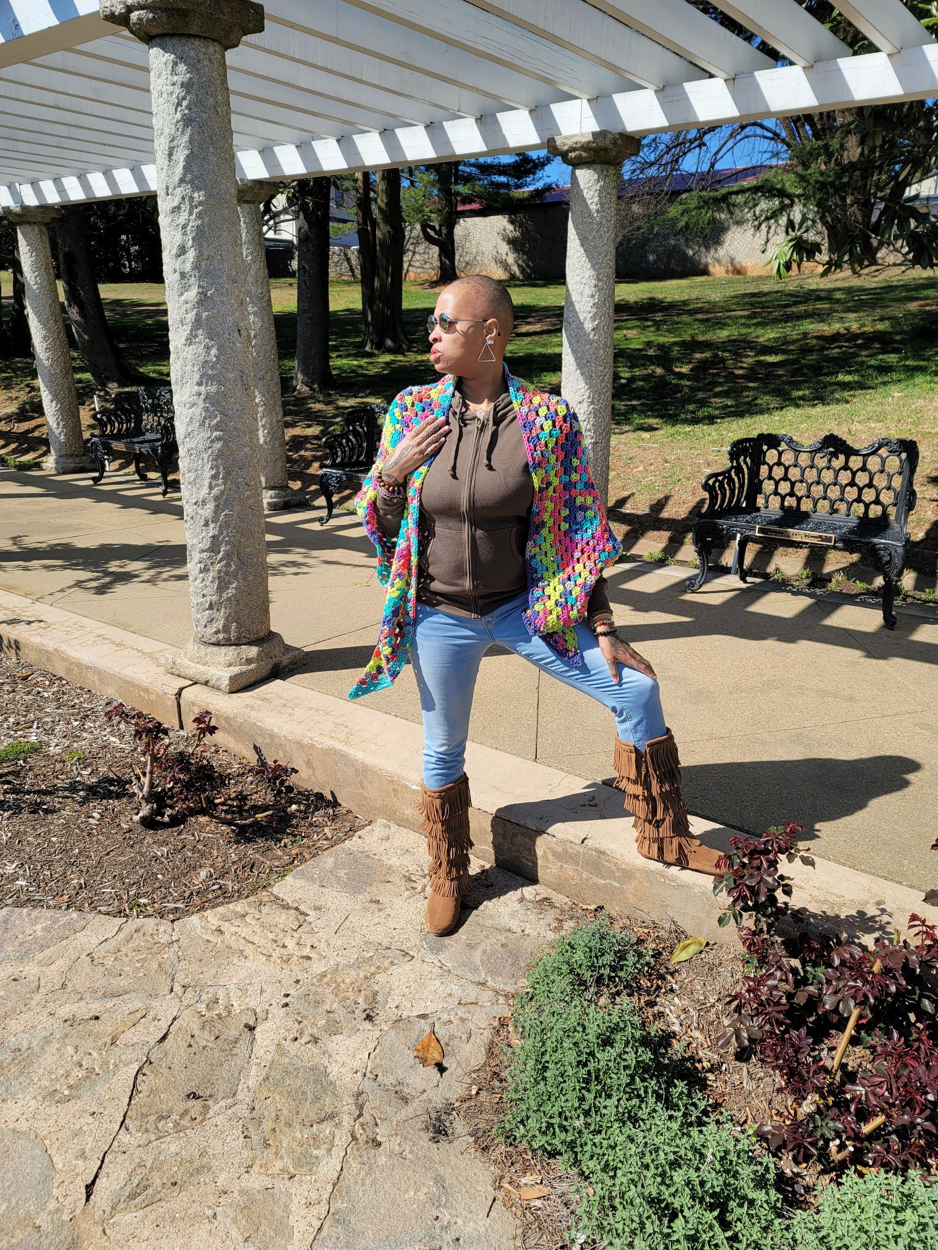 A woman is standing under a pergola in a park.