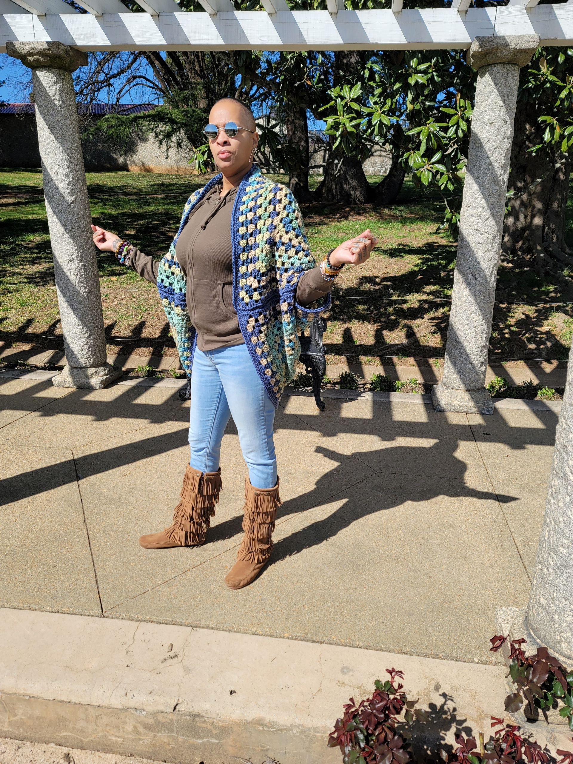 A woman is standing under a pergola in a park.
