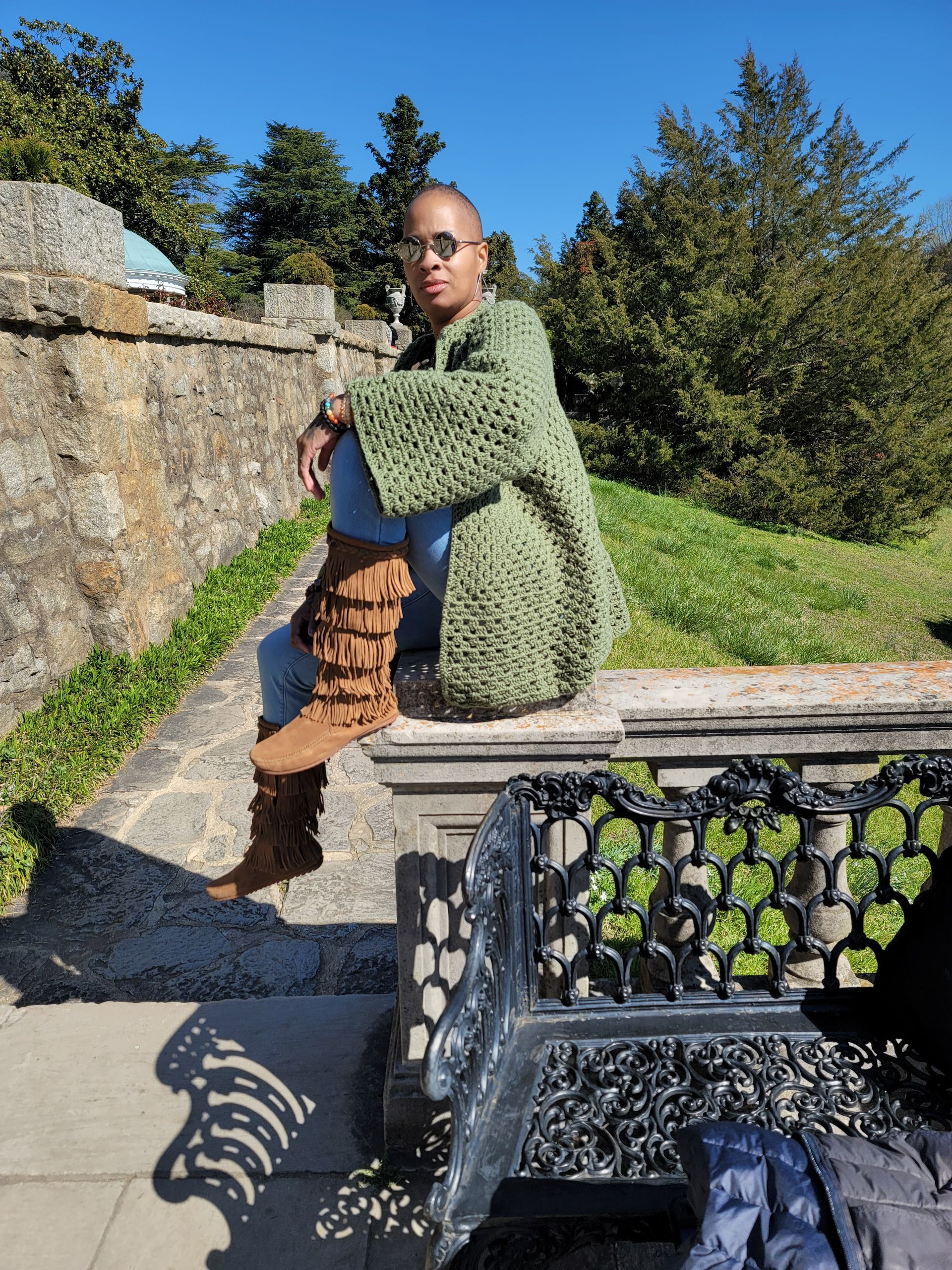 A woman in a green sweater is sitting on a bench.