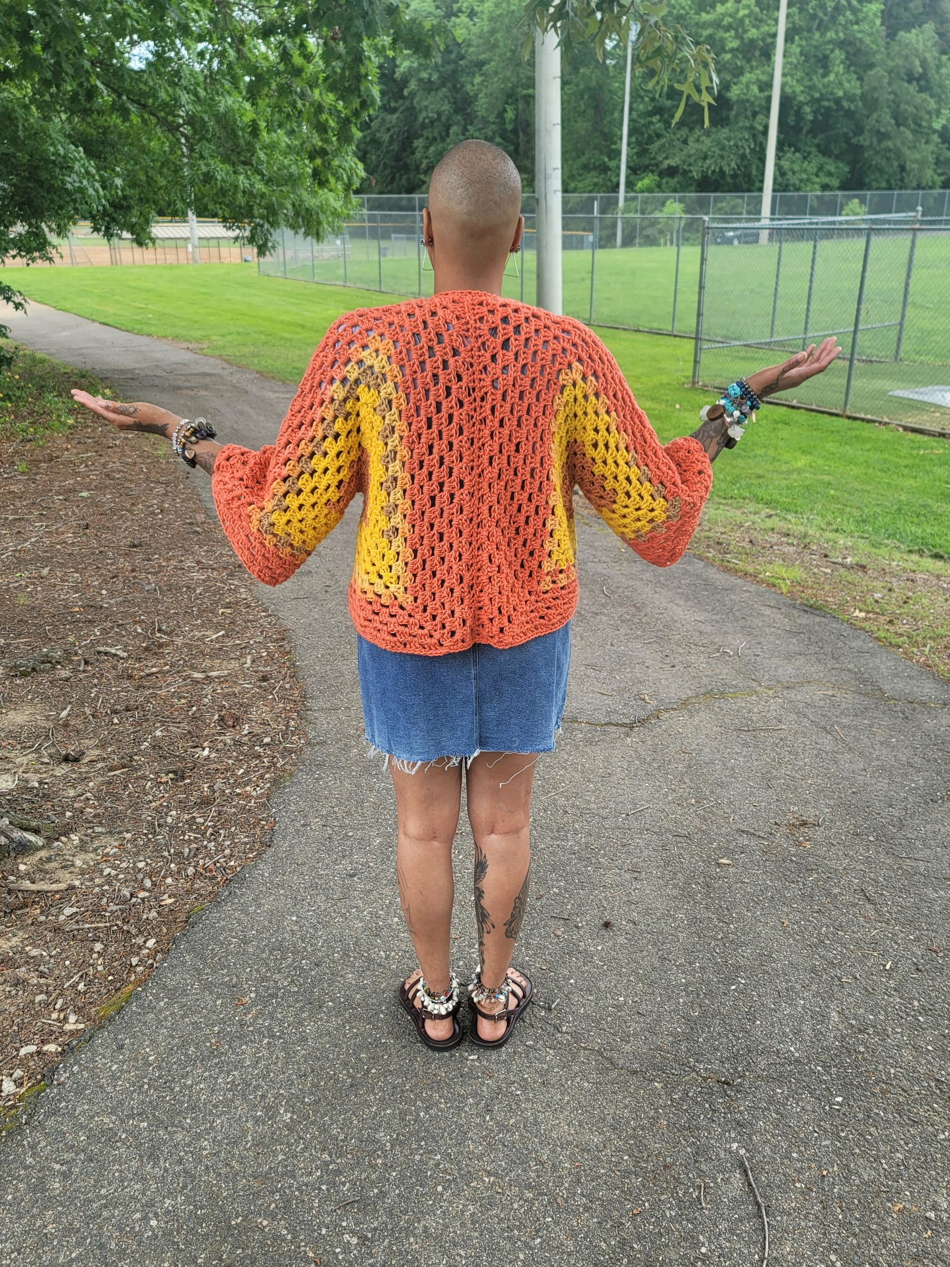 A woman is standing on a sidewalk with her arms outstretched.