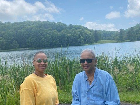 A man and a woman are standing next to a lake.