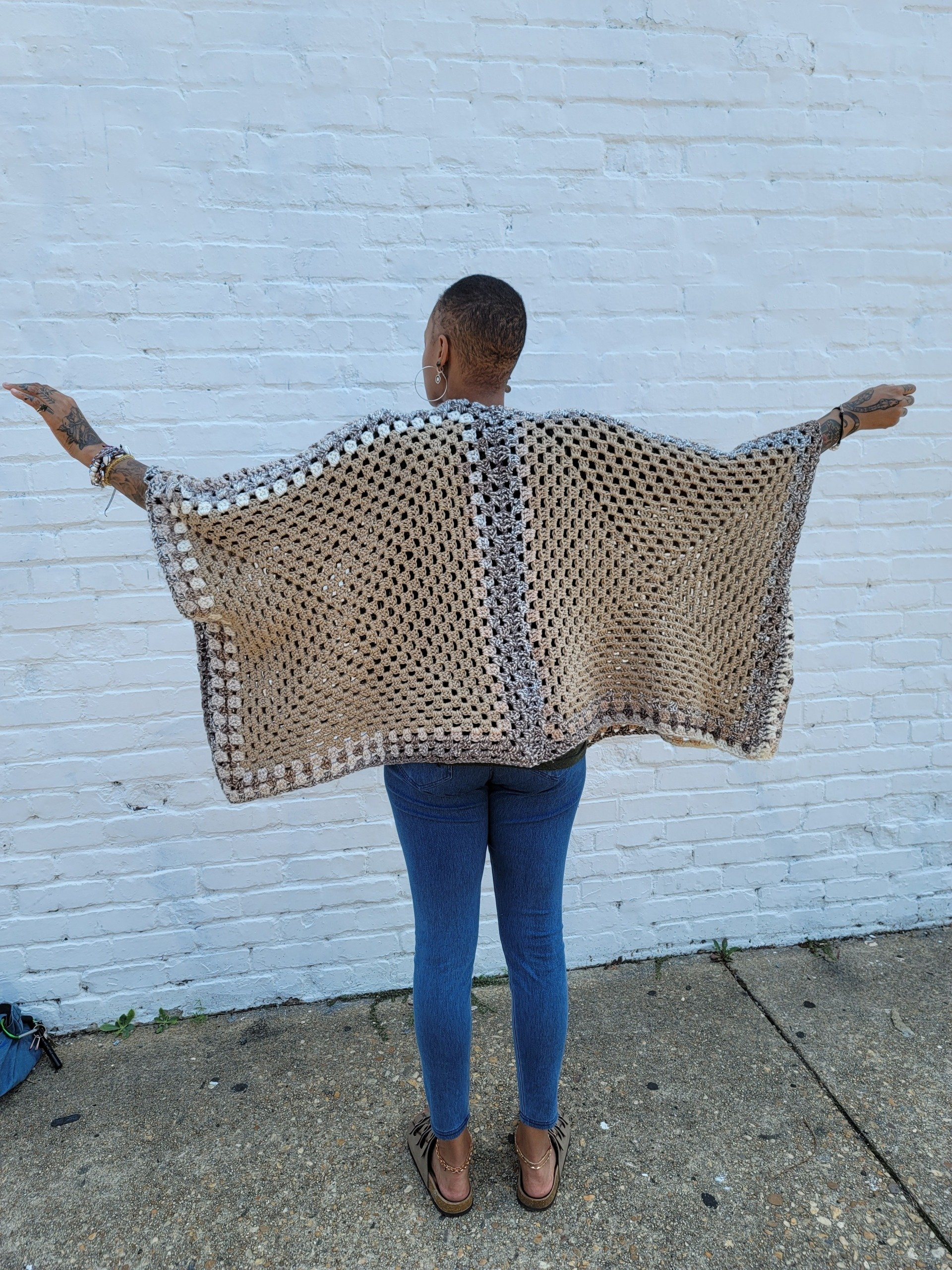 A woman is standing on a sidewalk wearing a leopard print poncho.