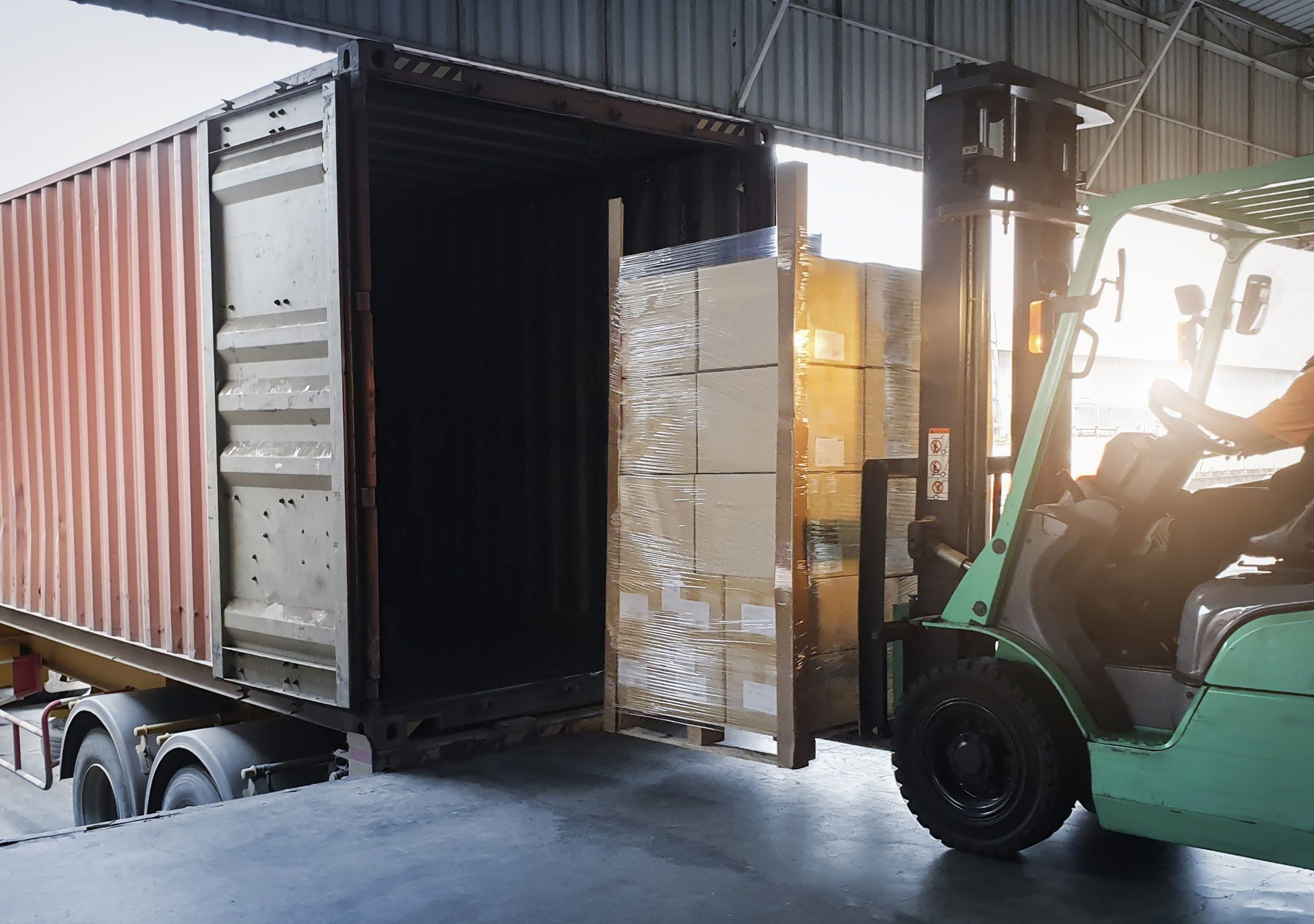 A forklift is loading a shipping container in a warehouse