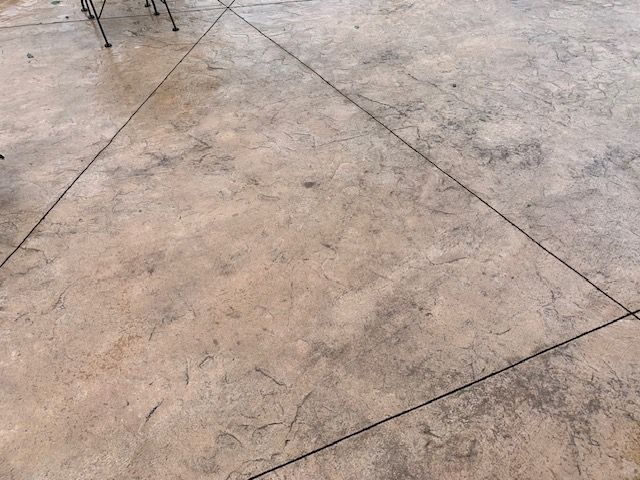 A close up of a concrete floor with chairs in the background
