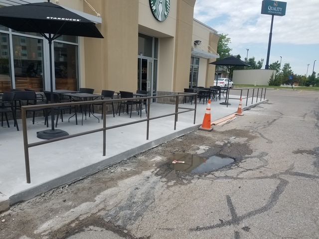The outside of a Starbucks with tables and umbrellas