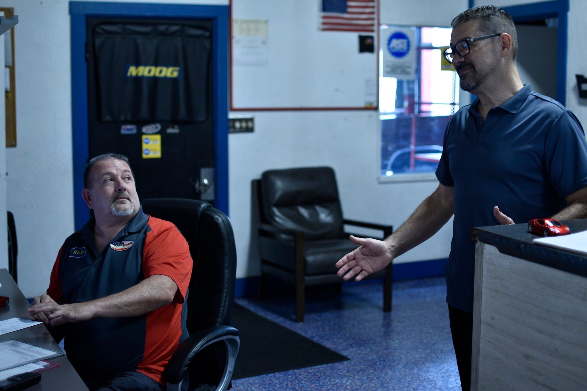 Two men are standing in a room with a door that says moog on it | David's Automotive Repair