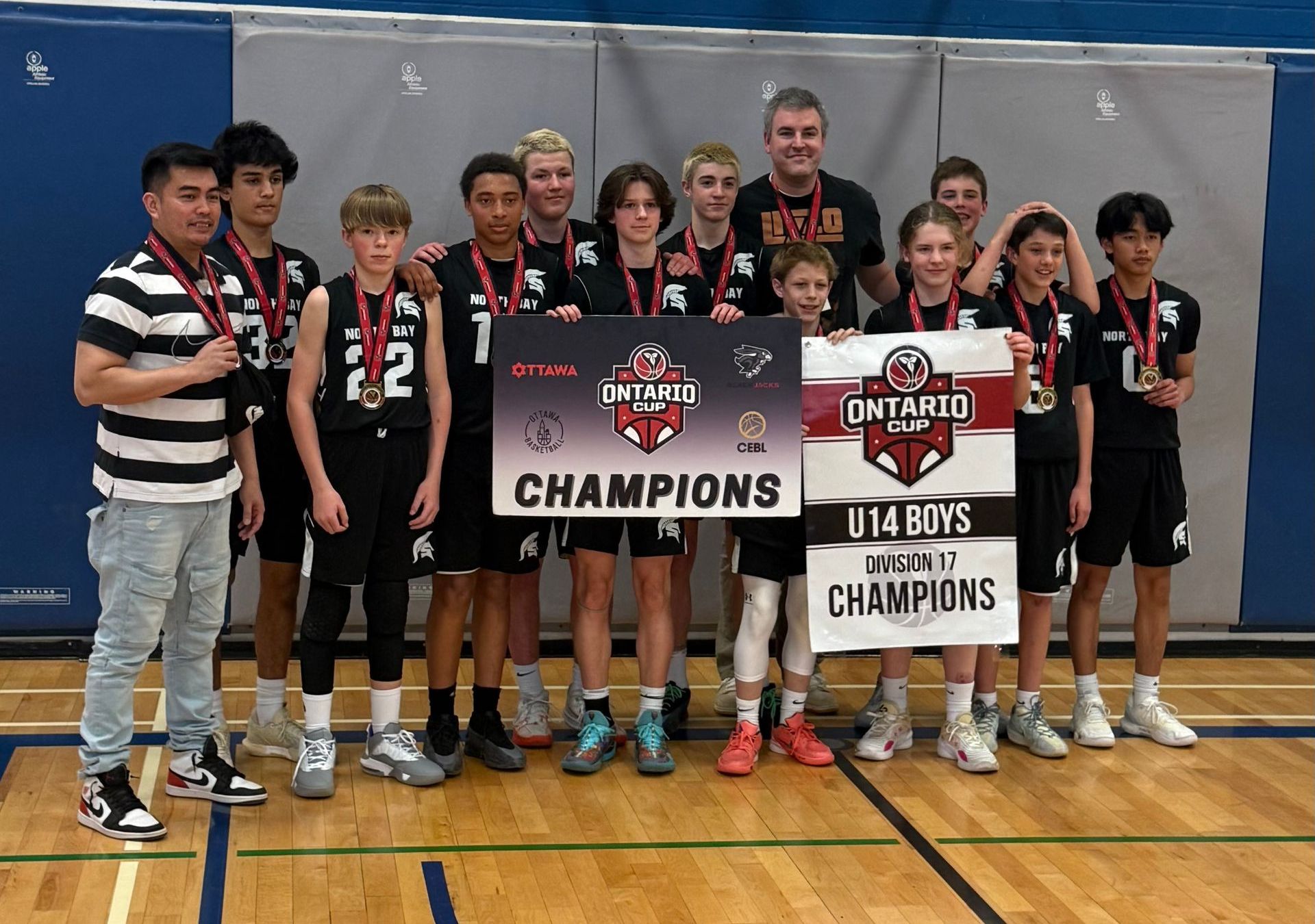 A youth basketball team, U14 Boys Champions, poses with a banner and medals.