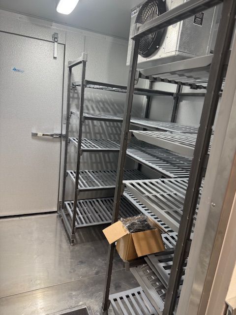 White commercial refrigerator interior with shelves and boxes.