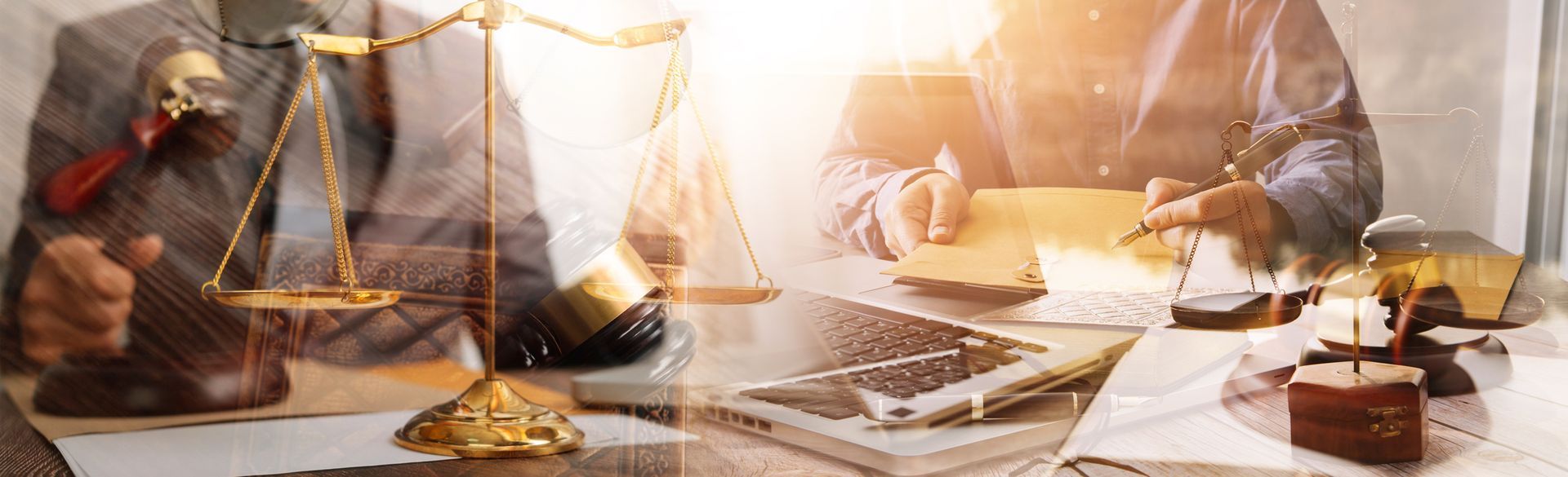 A group of people are sitting at a table with scales of justice and a laptop.