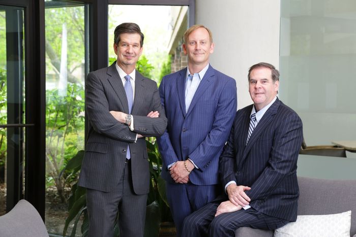 Three men in suits and ties are posing for a picture.