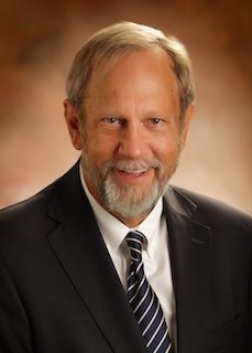 A man in a suit and tie is smiling for the camera.