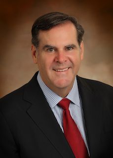 A man in a suit and tie is smiling for the camera.