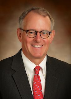 A man in a suit and tie is smiling for the camera.