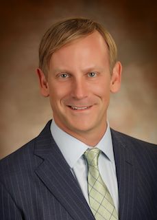 A man in a suit and tie is smiling for the camera.