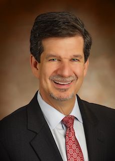 A man in a suit and tie is smiling for the camera.