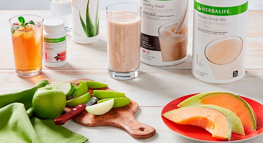 Batidos de proteínas Herbalife, suplementos y fruta fresca, incluyendo manzanas verdes en rodajas y melón