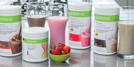 Sobre una mesa, se ven botes de polvo para sustituir comidas de Herbalife Nutrition y batidos preparados en vasos