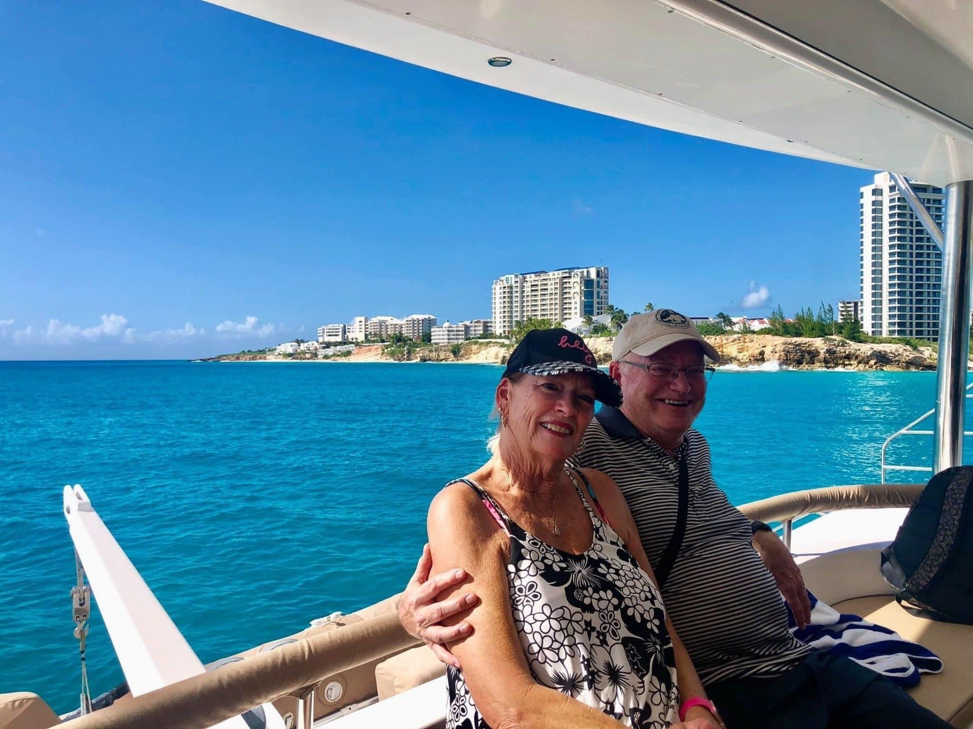 Couple reclining on sun deck cushions of Sail The Phoenix at Mullet Bay, admiring the turquoise sea