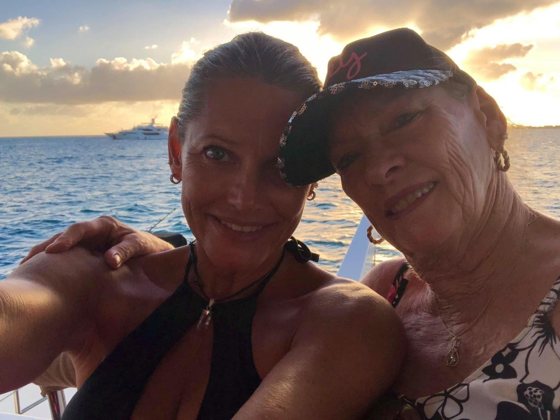 Mother and daughter smiling together on Sail The Phoenix deck with a golden sunset backdrop