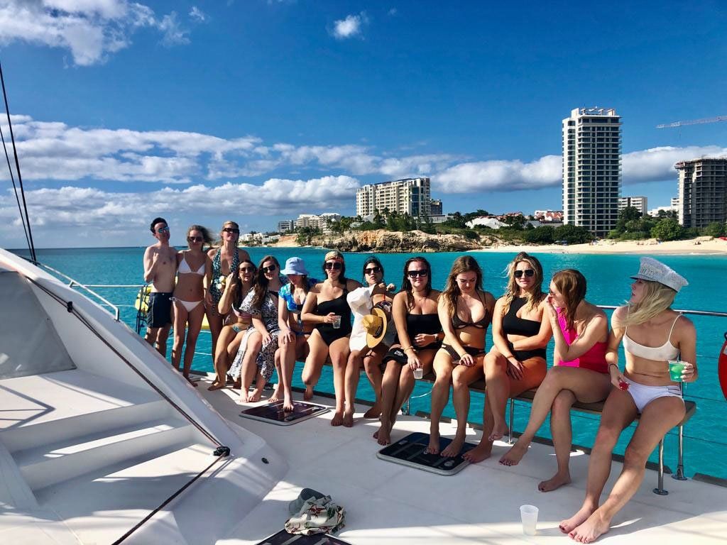 Bachelorette party sitting along the bow railing of Sailβ―Theβ―Phoenix overlooking Mullet Bay