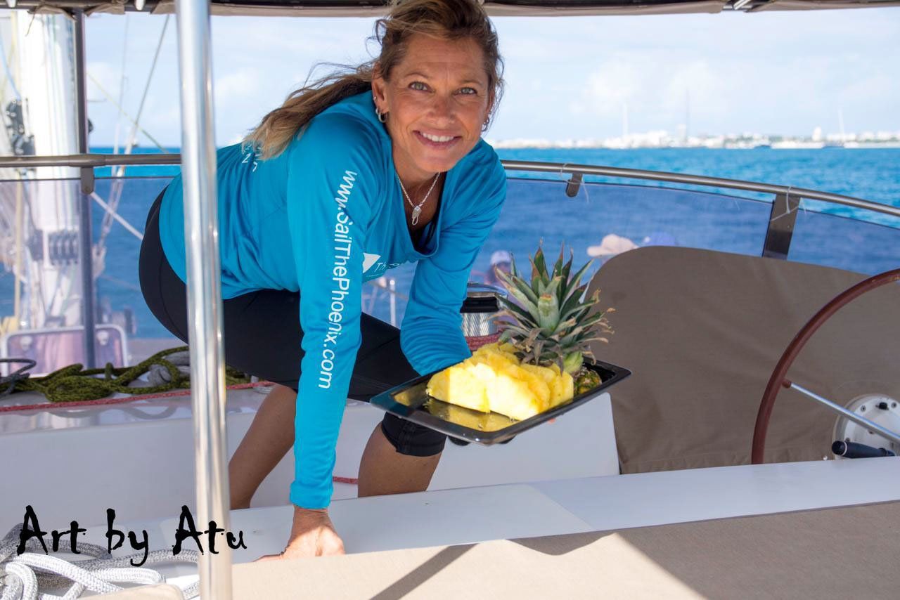 Hostess presenting a vibrant tropical fruit platter to seated guests on Sailβ―Theβ―Phoenix sun deck