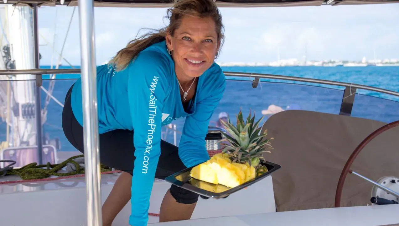 Crew serving fresh pineapple to guests aboard Sail The Phoenix