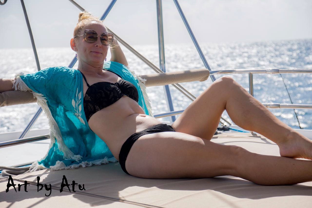 Guest reclining on the sun deck cushions of Sailβ―Theβ―Phoenix, gazing at the Caribbean horizon
