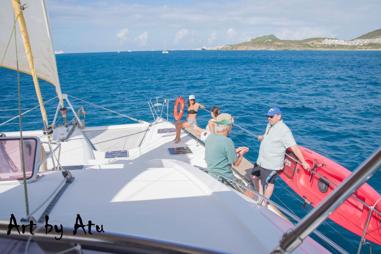 Guests relaxing on the bow along the boatβs edge, sailing the coastline of Sint Maarten