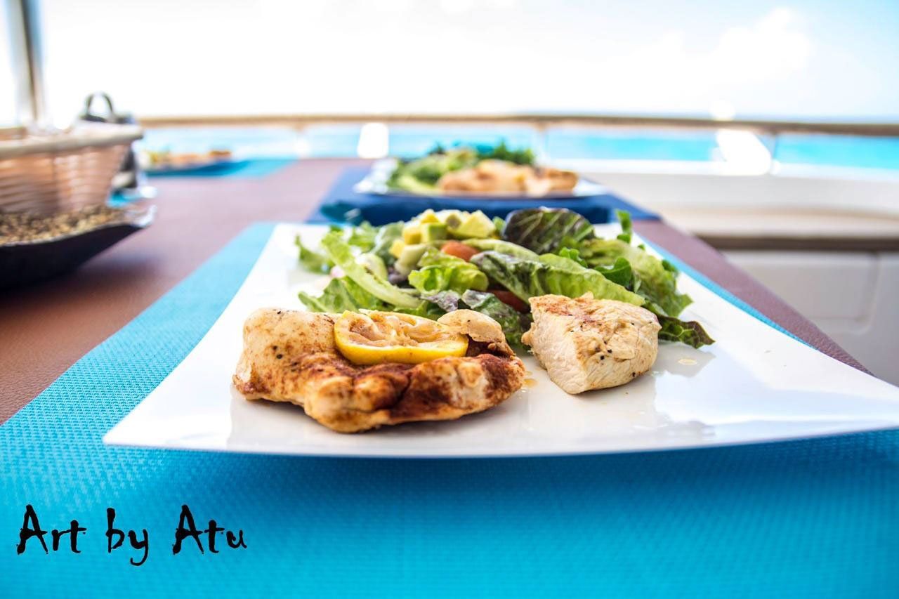 Grilled chicken breast and mixed green salad arranged on a wooden table aboard Sailβ―Theβ―Phoenix