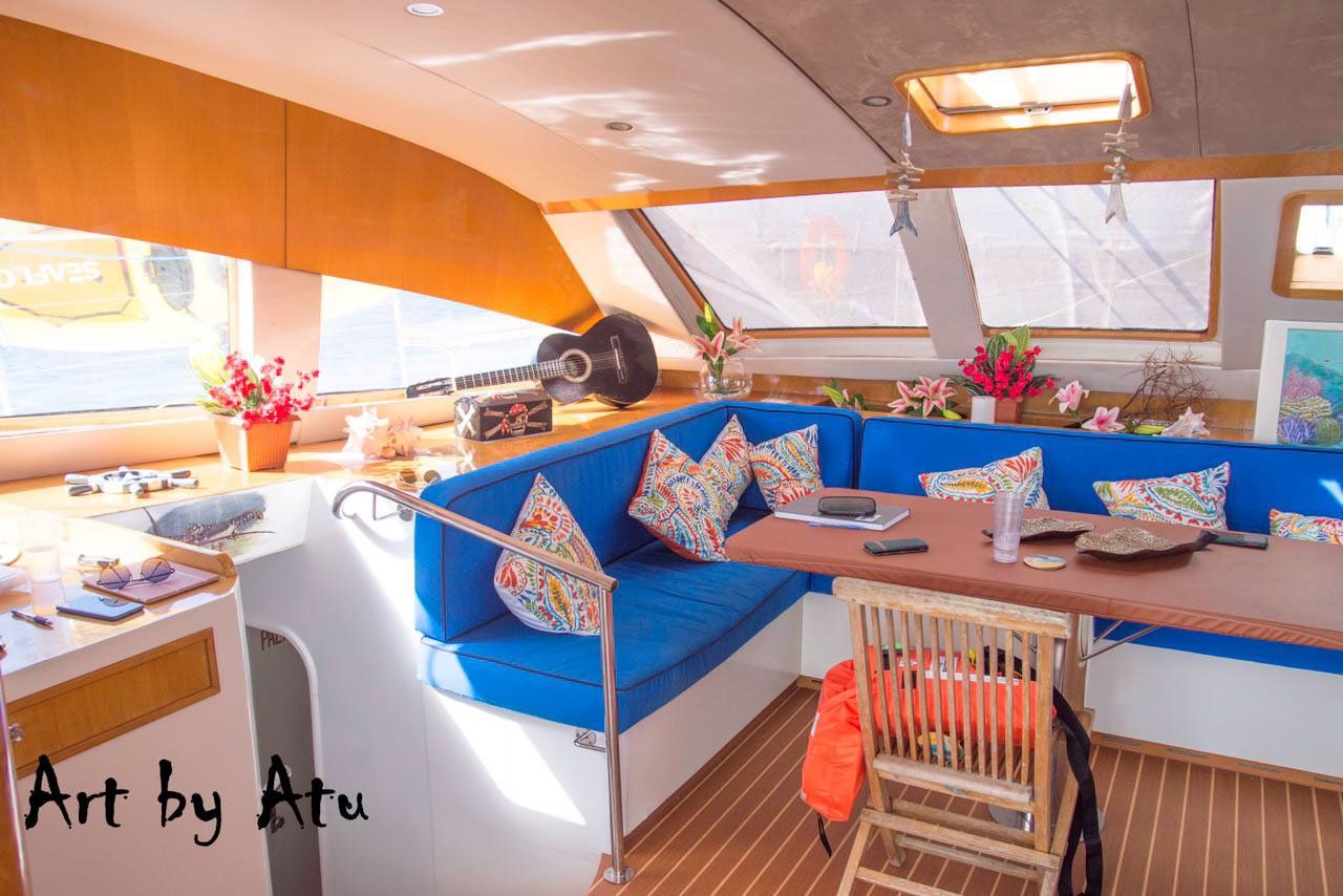 Bright interior saloon of Sailβ―Theβ―Phoenix featuring a wooden dining table and plush seating