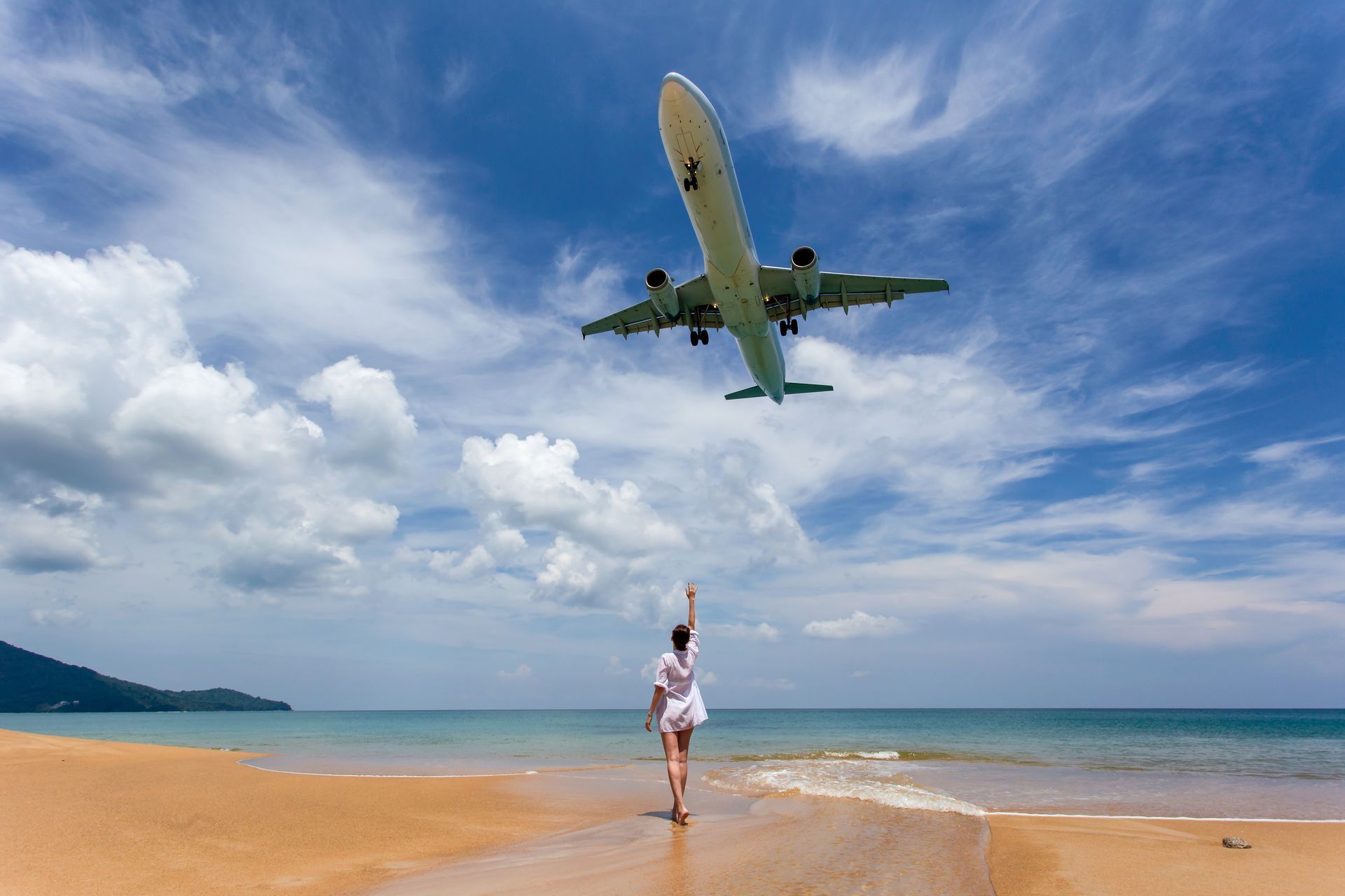 Woman standing under airplane landing at Maho Beach