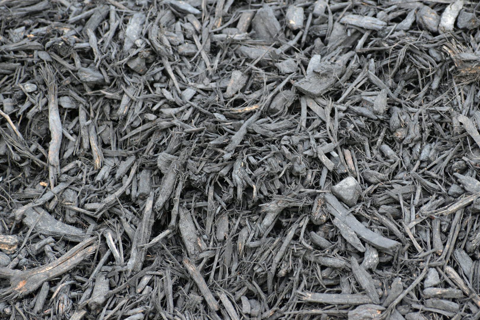 A pile of brown mulch is sitting on the ground.