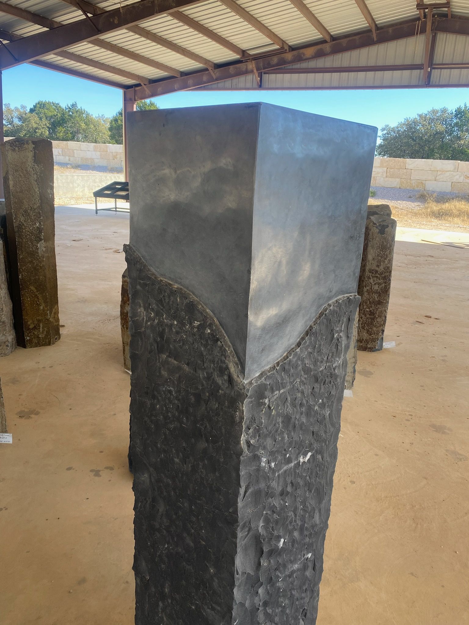 A large black stone sculpture is sitting under a roof.